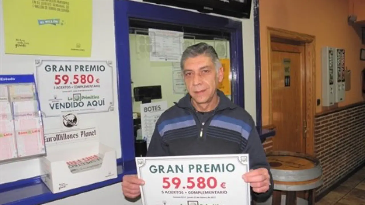 El propietario del bar con el cartel del premio (Loter&iacute;as). 