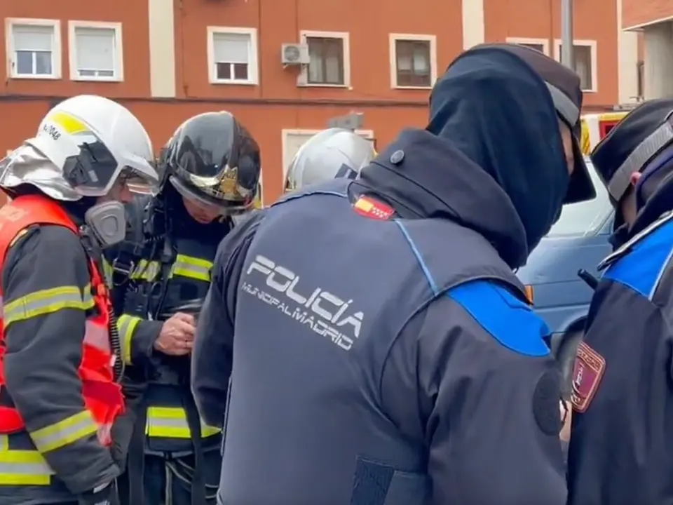 Un coche arde en el garaje de un edificio en Carabanchel. Bomberos y polic&iacute;as trabajan en la escena.