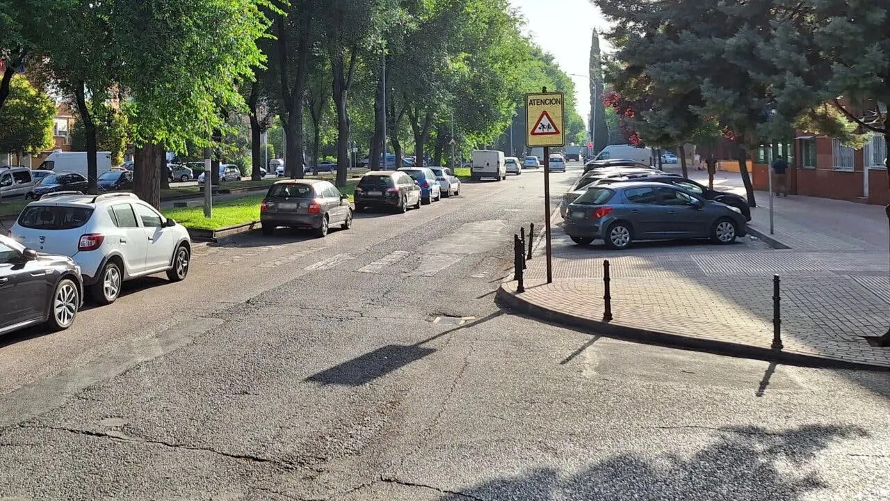 Vista de una calle con &aacute;rboles y veh&iacute;culos estacionados.