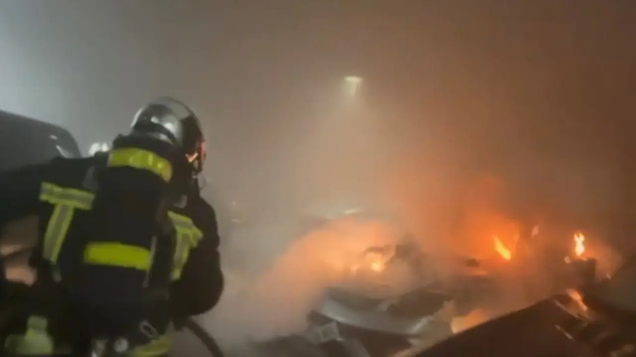 Un bombero lucha contra un incendio en un concesionario de coches de alta gama en Alcobendas.
