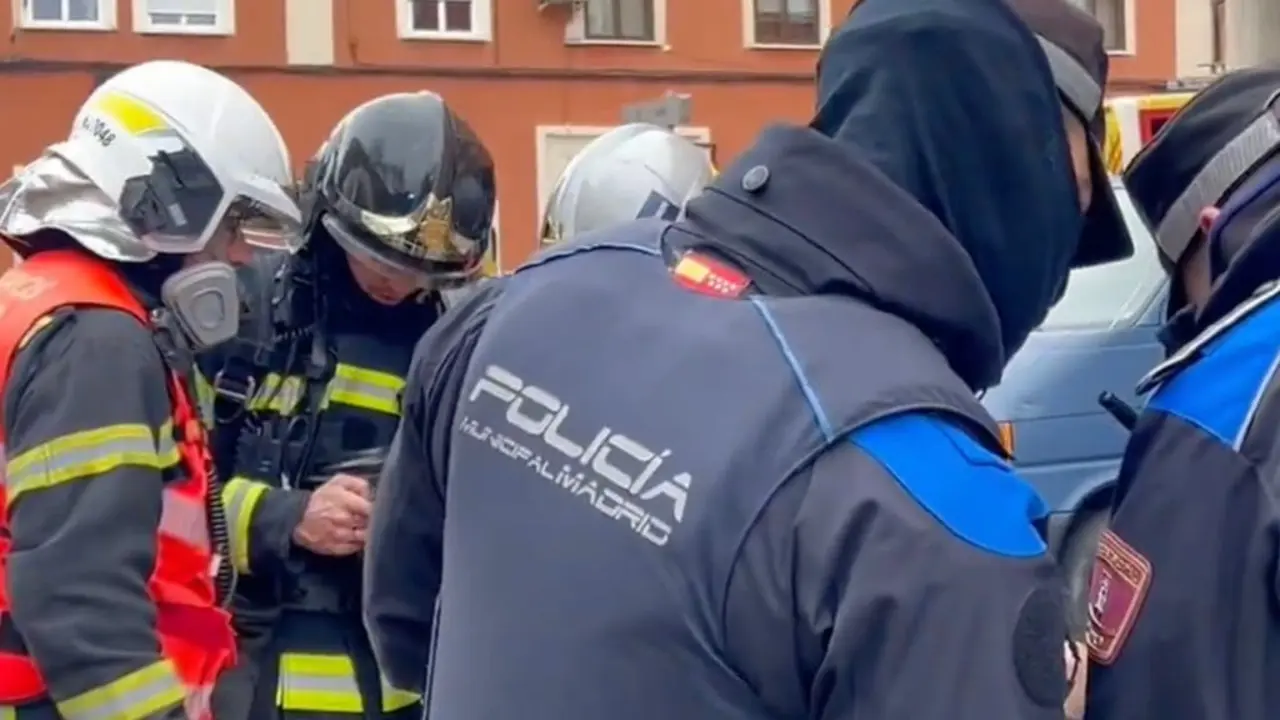 Un coche arde en el garaje de un edificio en Carabanchel. Bomberos y polic&iacute;as trabajan en la escena.