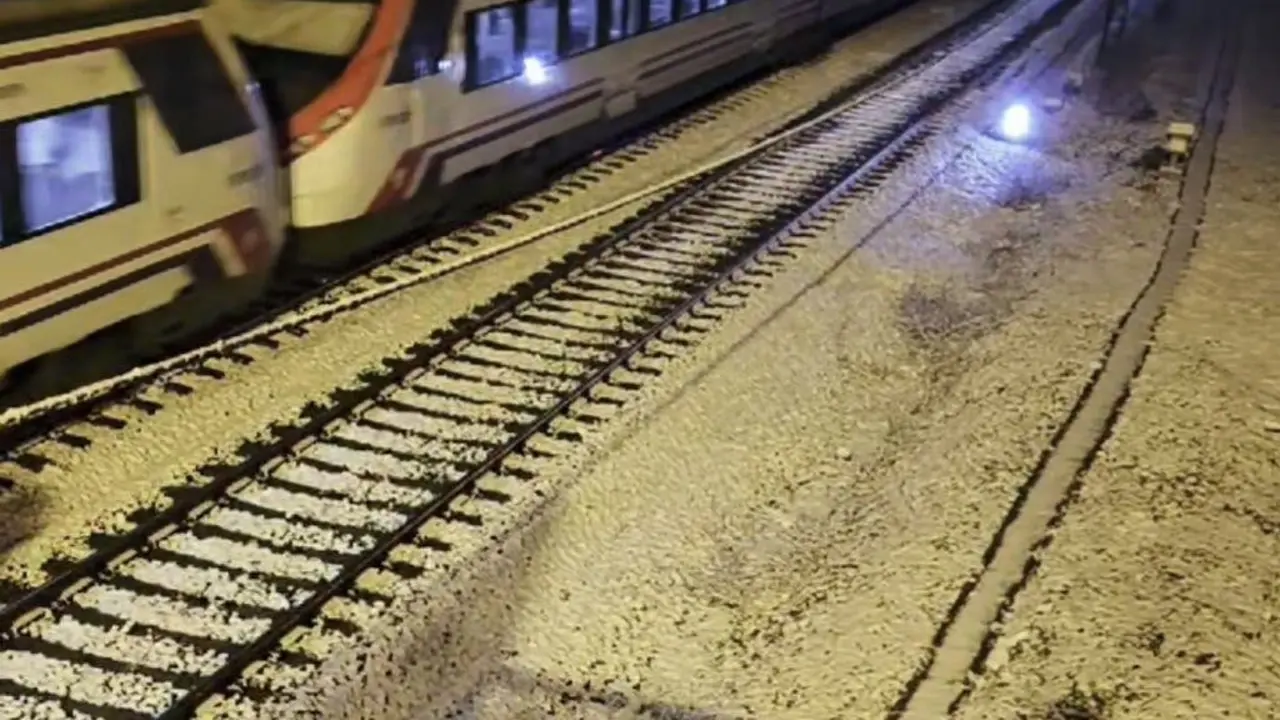 Un tren circula por la v&iacute;a nevada en el Corredor del Henares.