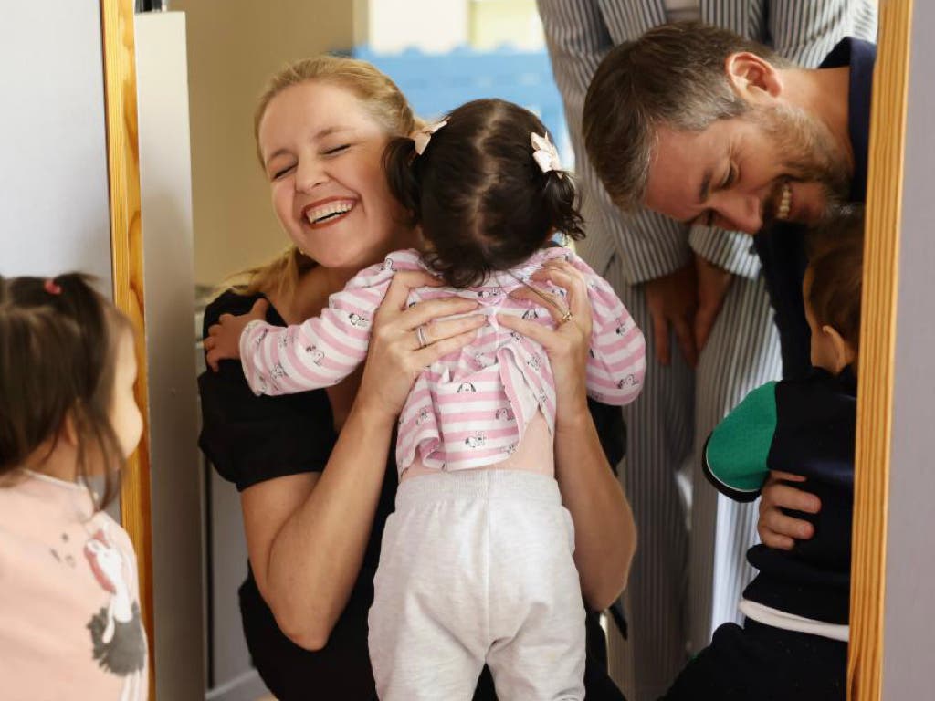 Mujer sonriente abrazando a niños en un ambiente familiar