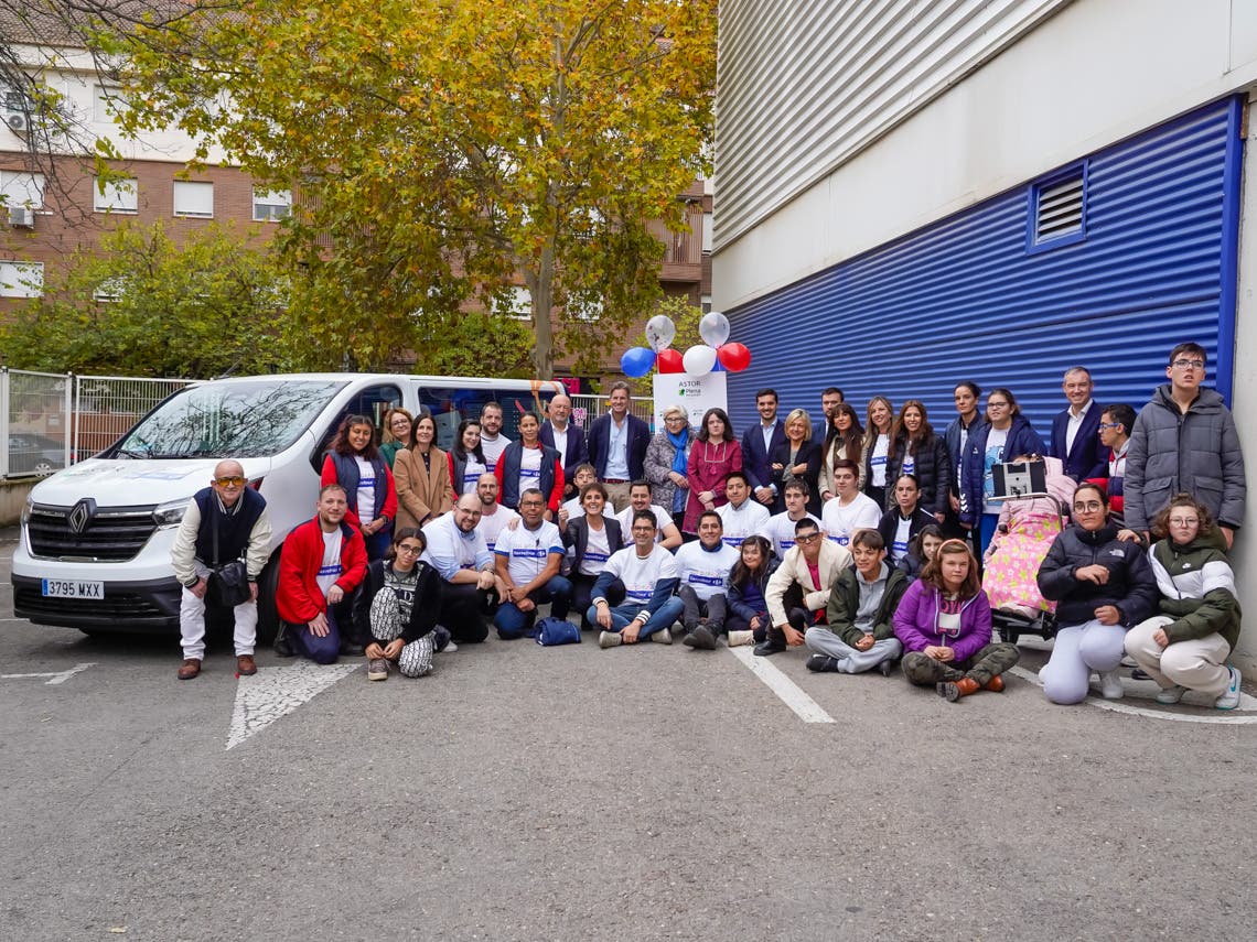 Grupo de personas junto a un vehículo escolar adaptado donado por Carrefour en Torrejón.