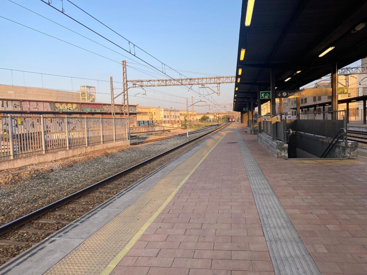 Estación de tren con andenes y vías visibles en un día soleado