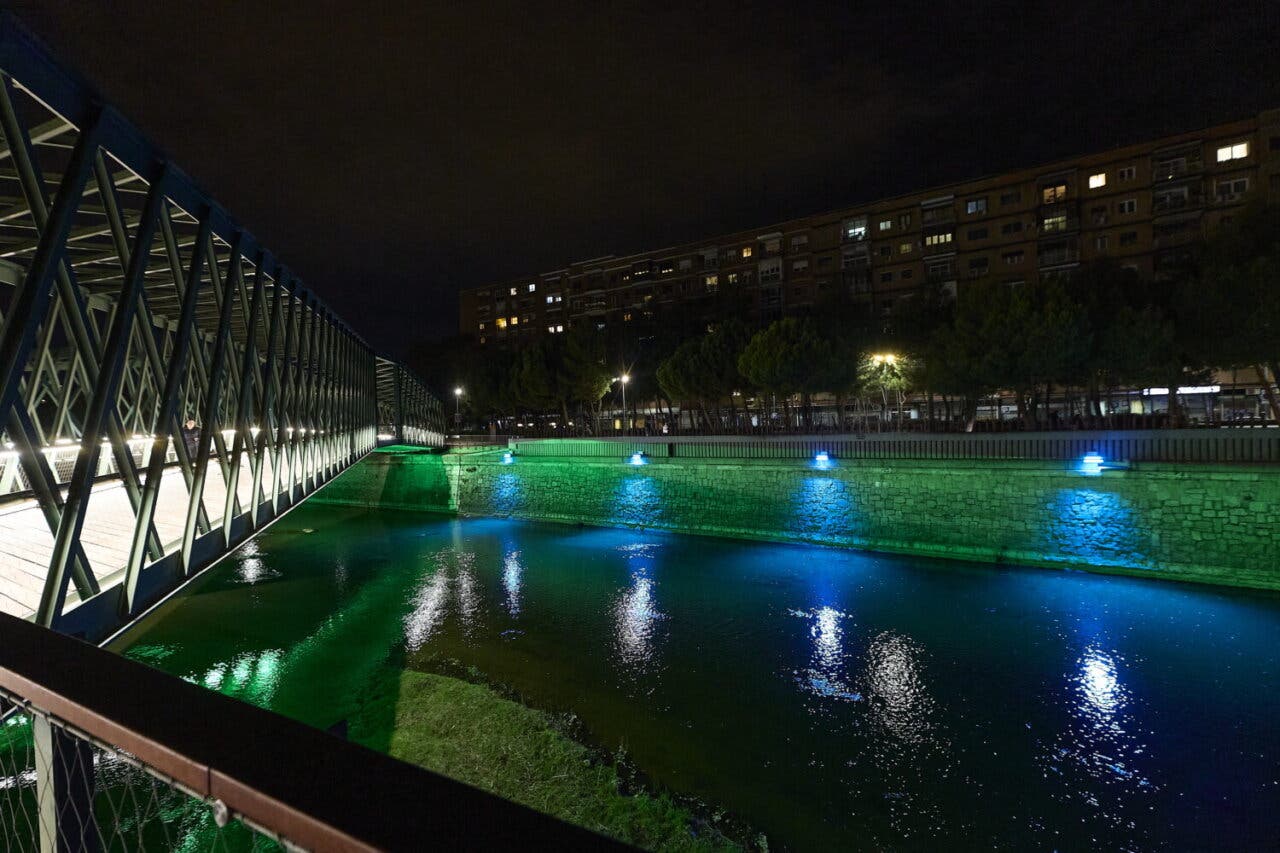 Vista nocturna del río Manzanares iluminado de azul y verde