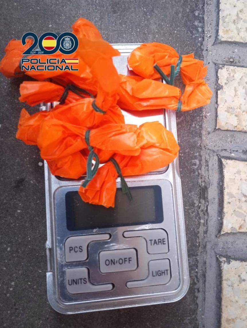 Balanza digital con paquetes de cocaína en envoltorios naranjas