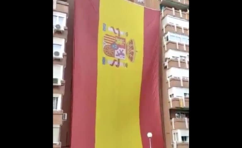 Vecinos del barrio del Pilar, en Madrid, despliegan una enorme bandera de España