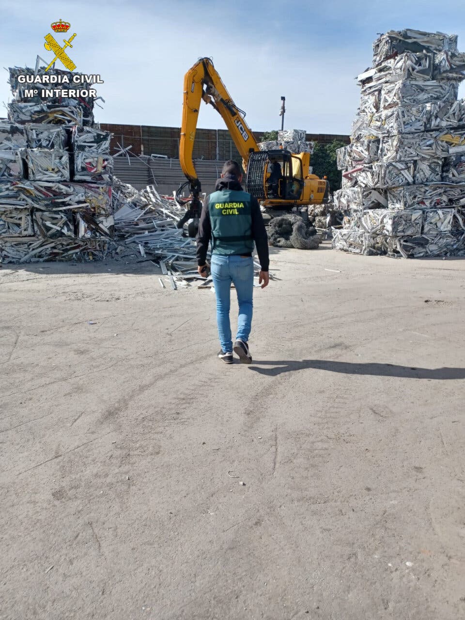 Agente de la Guardia Civil en un centro de reciclaje con maquinaria pesada.