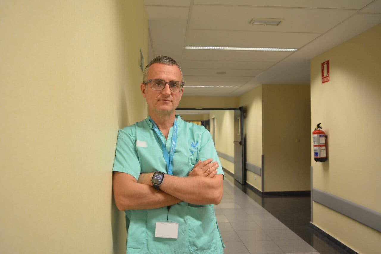 Médico en uniforme de hospital posando en un pasillo